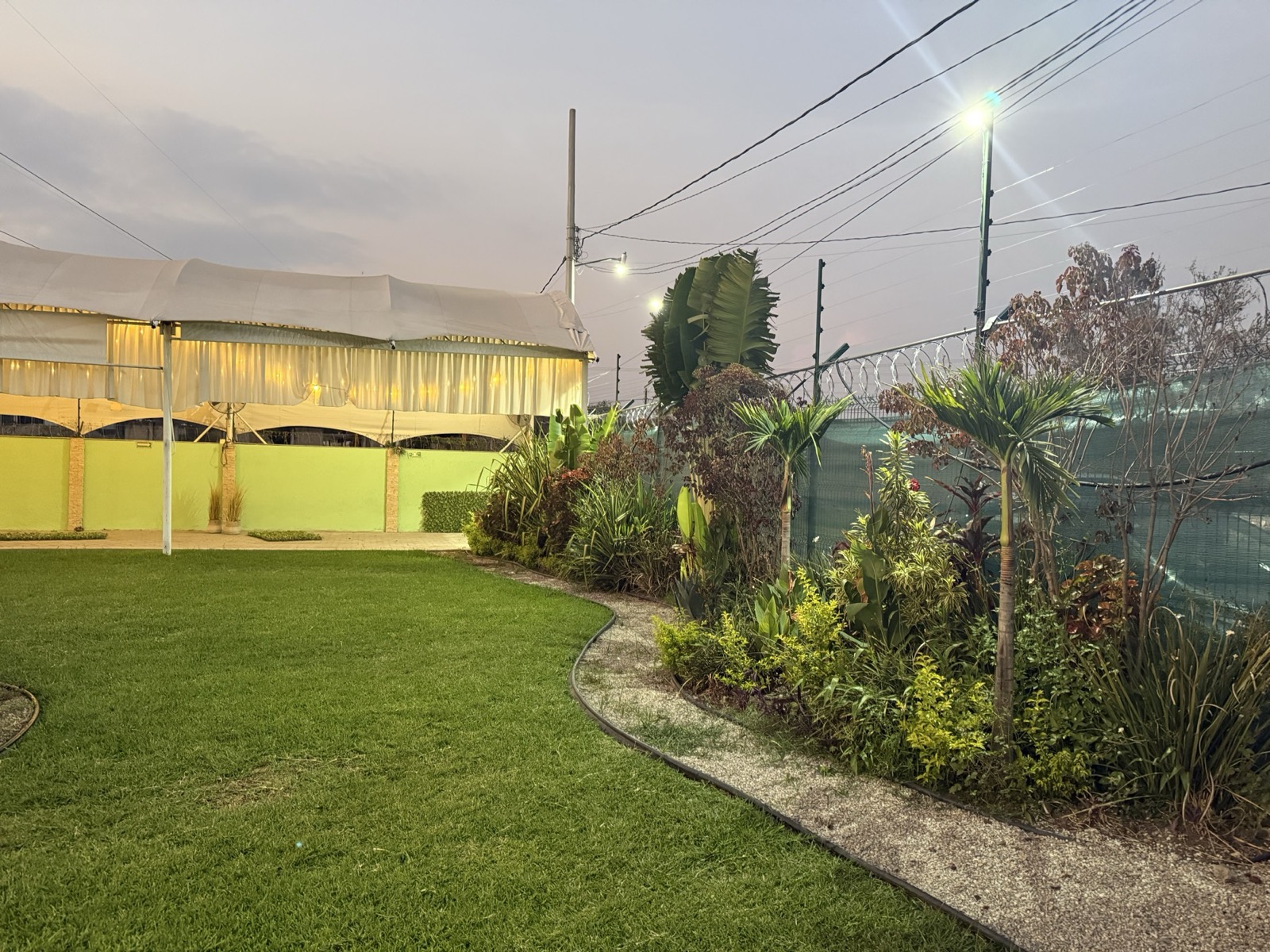 Jardín Paraíso Colibrí con carpa blanca y jardín iluminado